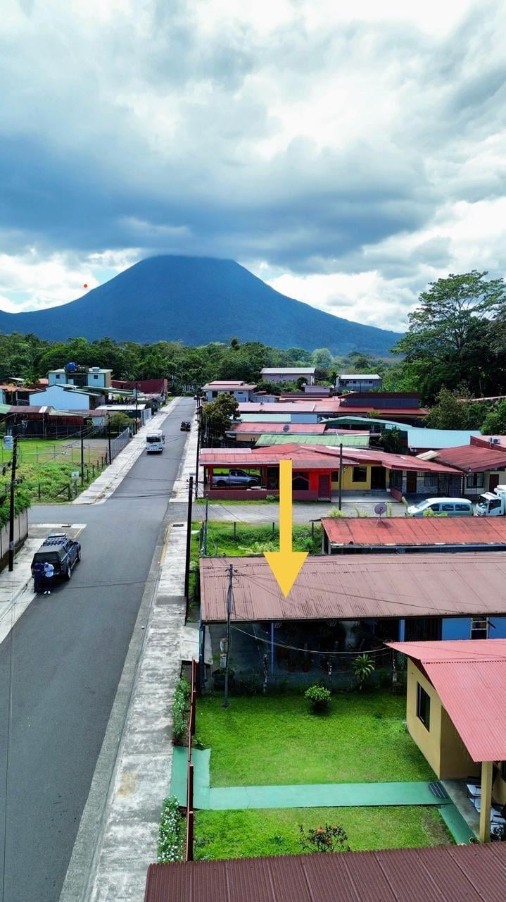 Aerial view of a residential town with colorful houses and a blue volcano in the background under cloudy sky